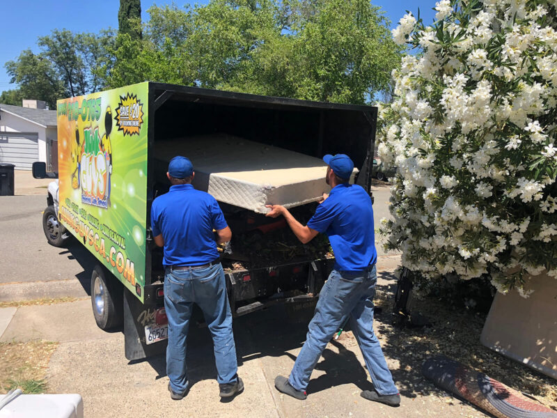 junk guys carrying mattress into truck